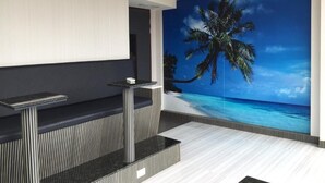 A modern room with a large wall mural of a beach scene, a built-in bar area, and a ceiling-mounted air conditioning unit. - Kenting Starry Sky - Space Capsule (Hengchun)