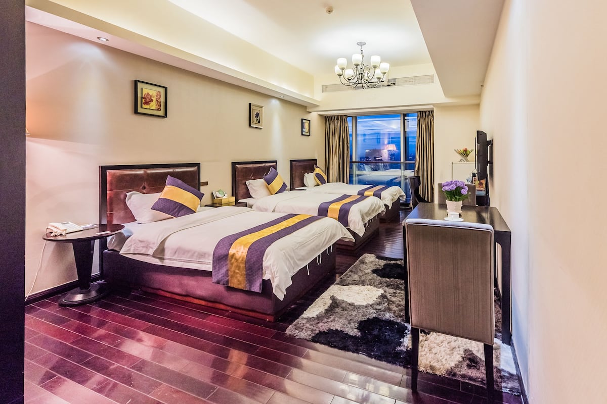 Een hotelkamer met twee bedden, een bureau, een kroonluchter en uitzicht op de stad.
