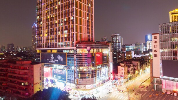 Un hôtel de grande hauteur, avec de nombreux étages, de grandes fenêtres et une enseigne lumineuse.