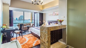 Une chambre d’hôtel moderne avec vue sur la ville, une cheminée en marbre, un bureau avec un ordinateur portable, un canapé et un coin repas.