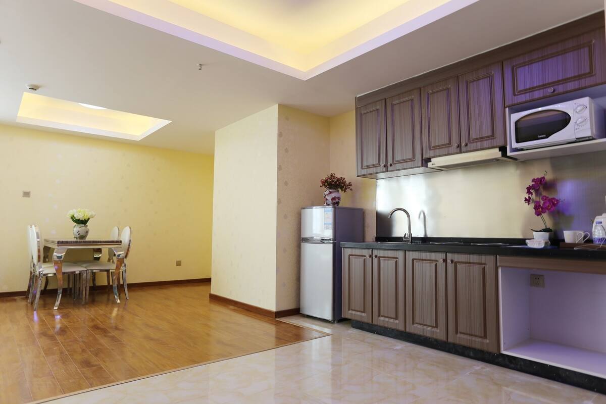 Una cocina moderna con armarios de madera, microondas integrado y comedor con mesa y sillas.