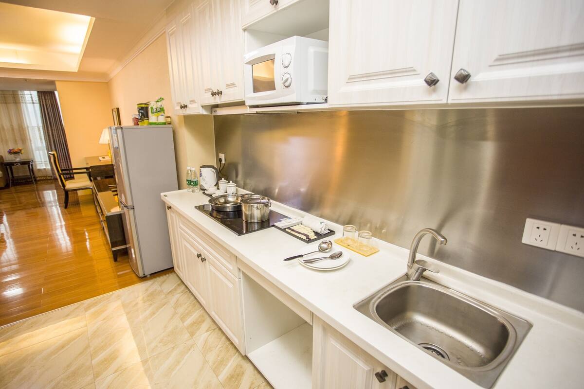 Una cocina moderna con armarios blancos, un lavamanos de acero inoxidable, un microondas y una estufa.