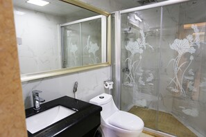 Un baño con inodoro blanco, lavamanos negro y cabina de ducha de vidrio con diseños florales.