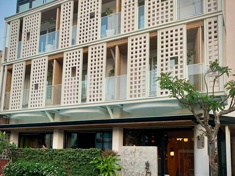 Un edificio moderno con varios balcones y un cartel que dice 'Cat'e Bar Rooms'.