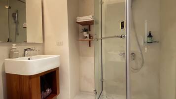 A modern bathroom with a glass-enclosed shower, a wooden vanity, and a large mirror.