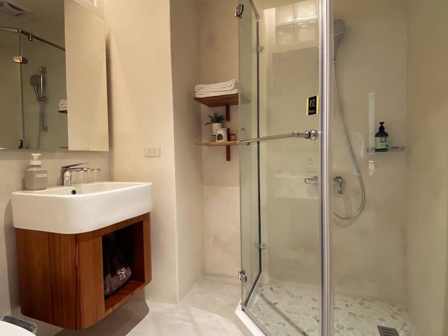 A modern bathroom with a glass-enclosed shower, a wooden vanity, and a large mirror.