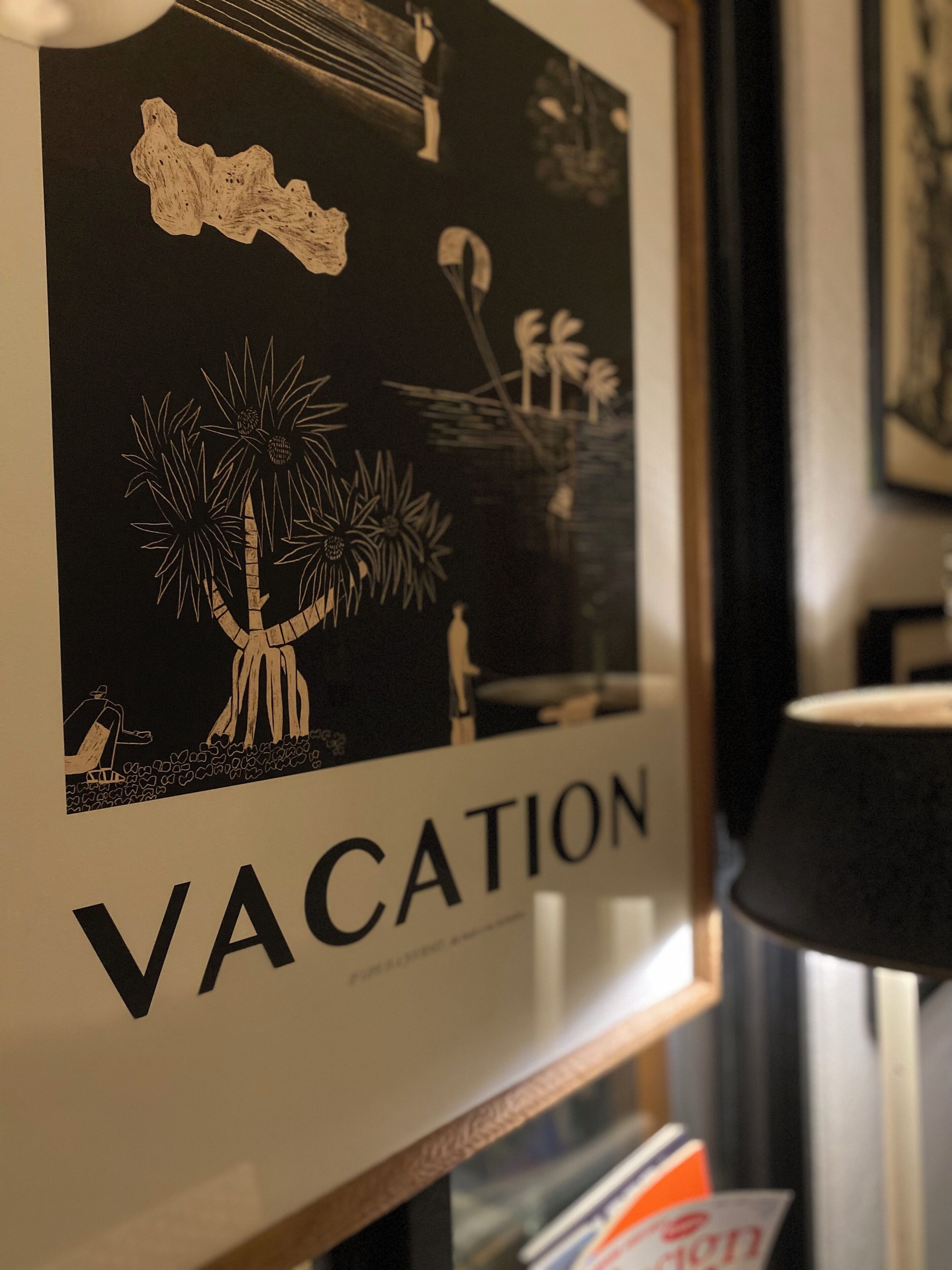 A framed artwork with a tropical theme, including palm trees and a person in a hammock, labeled "VACATION".