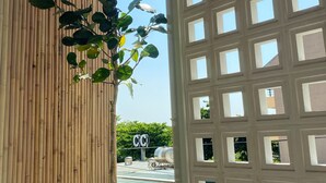 Techo de bambú, ventanal de celosía y vista de un edificio con un letrero.