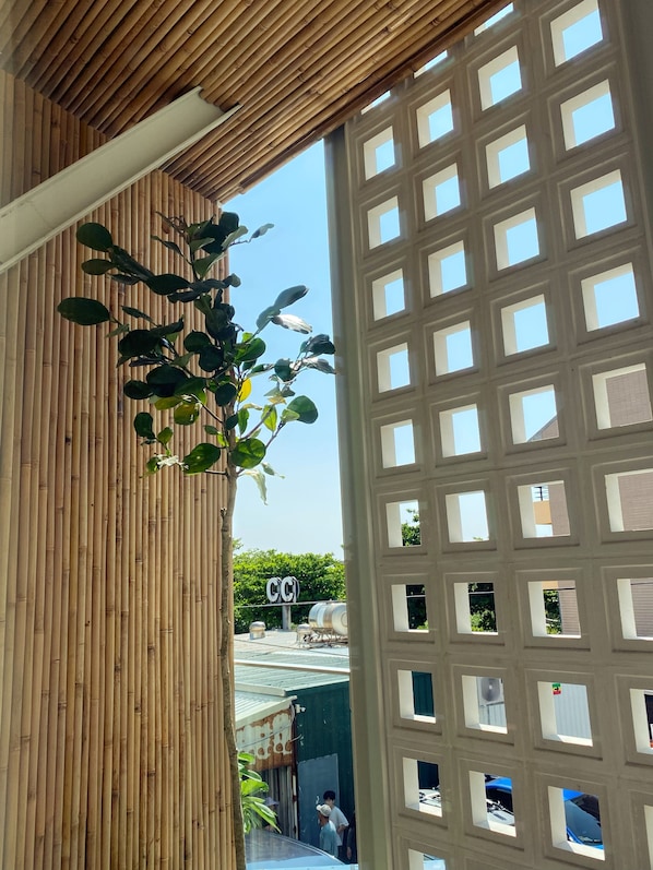 Techo de bambú, ventanal de celosía y vista de un edificio con un letrero.