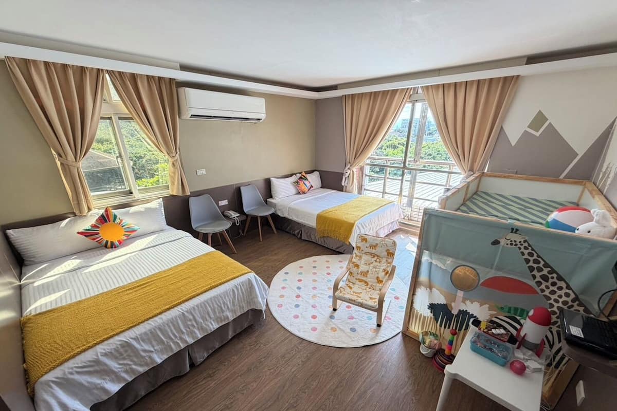Habitación de hotel con dos camas, un escritorio, una silla y un ventanal.