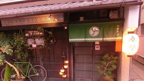 Un restaurant japonais traditionnel avec un auvent vert, un vélo et des plantes en pot.
