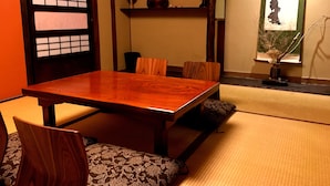 Une pièce de style japonais traditionnel, avec un sol recouvert de tatamis, une table à manger en bois et de petites chaises en bois.
