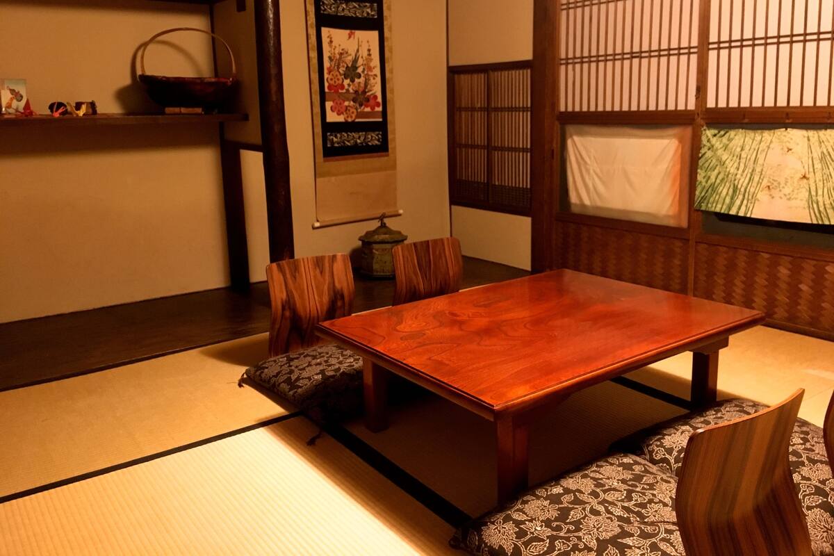 Une pièce de style japonais traditionnel, avec un sol recouvert de tatamis, une table en bois et des paravents en papier.