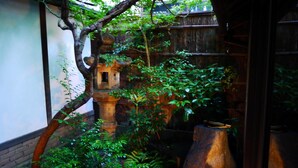 Un jardin japonais traditionnel, avec des lanternes en pierre, une clôture en bois et une végétation luxuriante.
