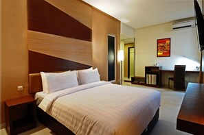 Habitación de hotel con una cama grande, un escritorio, una silla y un televisor.