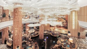 A spacious lobby with high ceilings, multiple seating areas, and a large chandelier.
