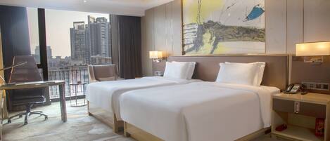 A hotel room with two beds, a desk, a chair, a nightstand, and a large window with a city view.