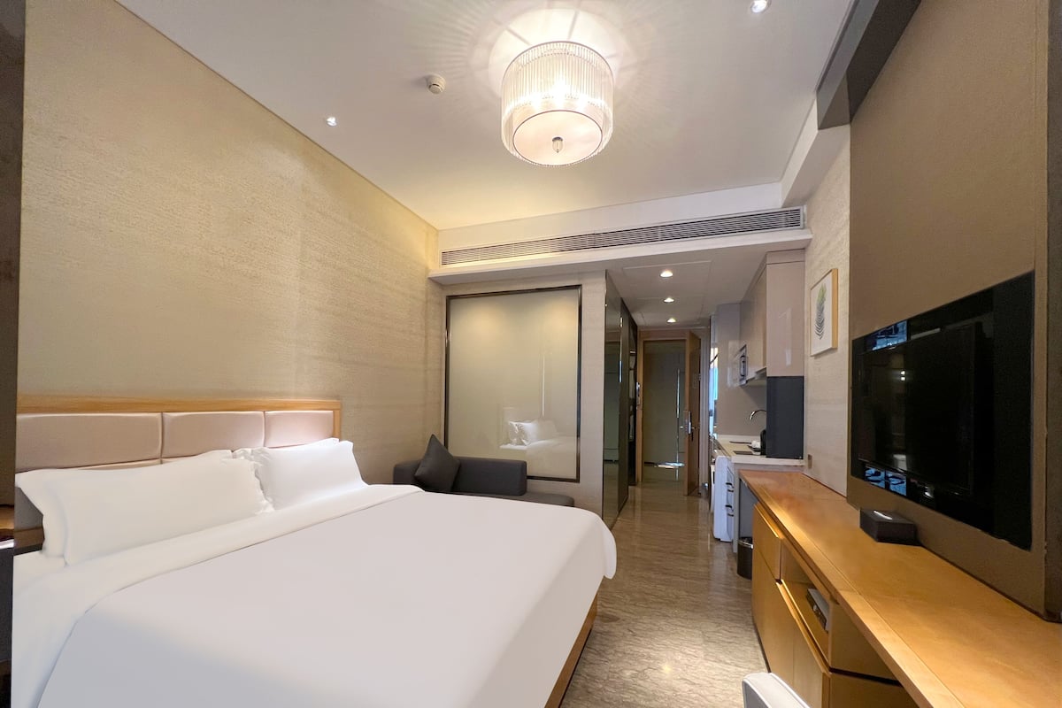 Une chambre d’hôtel avec un grand lit, une télévision, un bureau avec une chaise et un miroir.