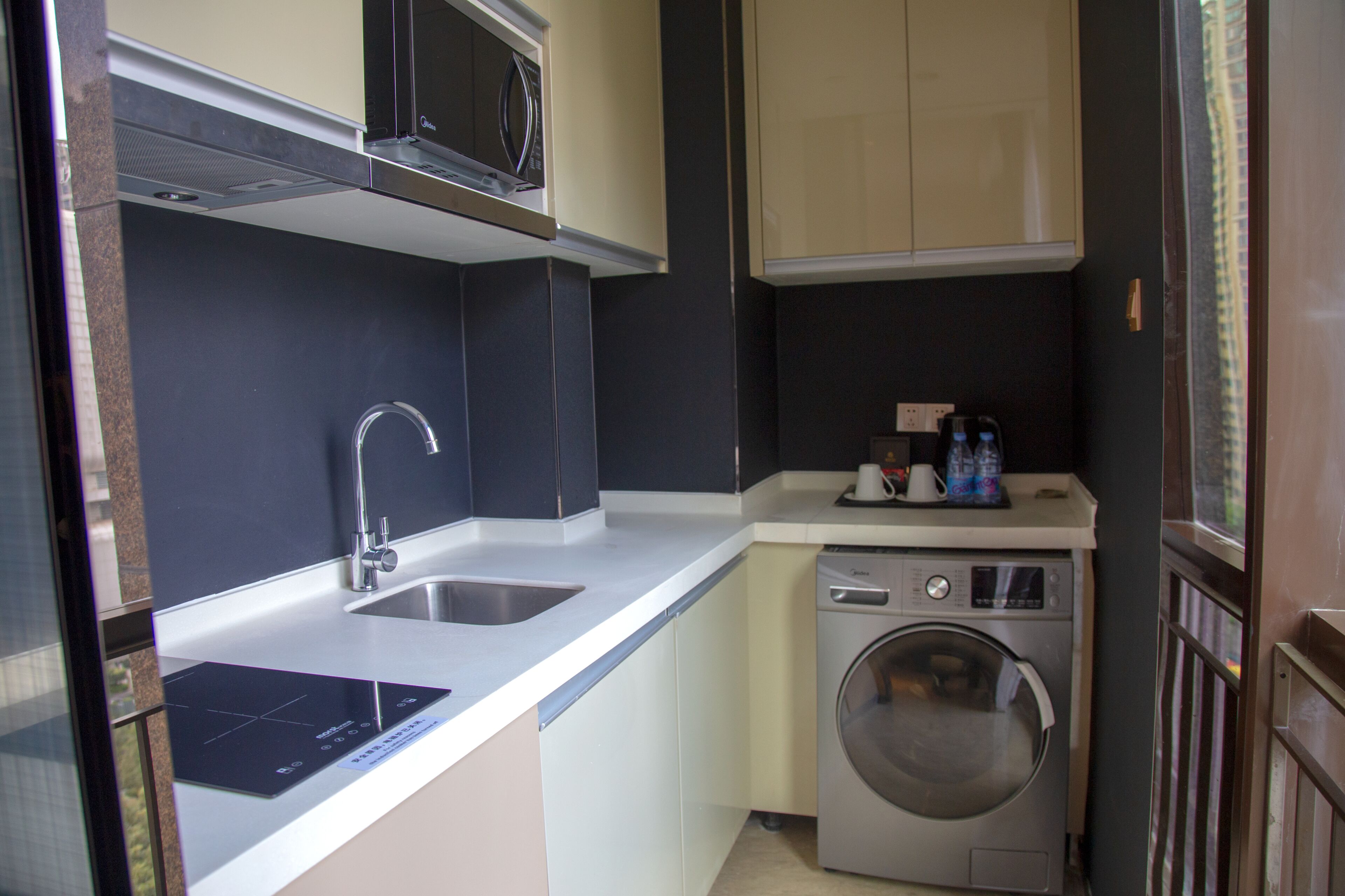 Una cocina compacta con microondas, lavabo y lavadora.