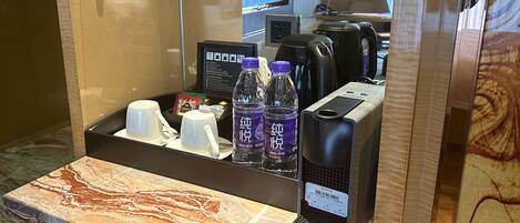 A hotel minibar with a coffee maker, tea set, and bottled water.