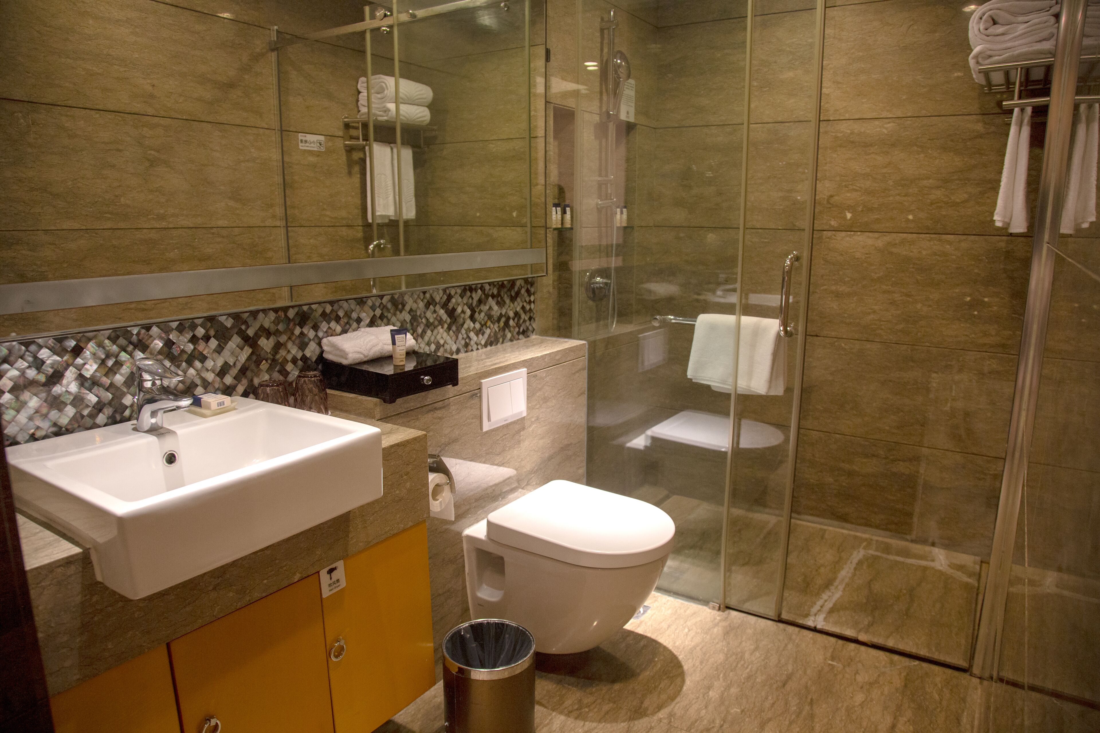 Un baño moderno con ducha envuelta en vidrio, un lavamanos blanco y un inodoro.