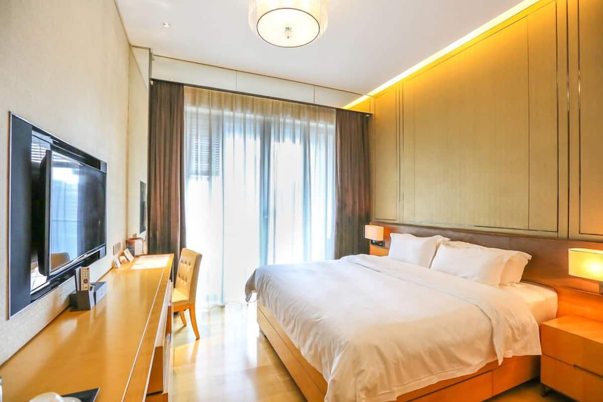 Une chambre d’hôtel comprenant un lit, une table de chevet, une lampe, une télévision et un bureau avec une chaise.