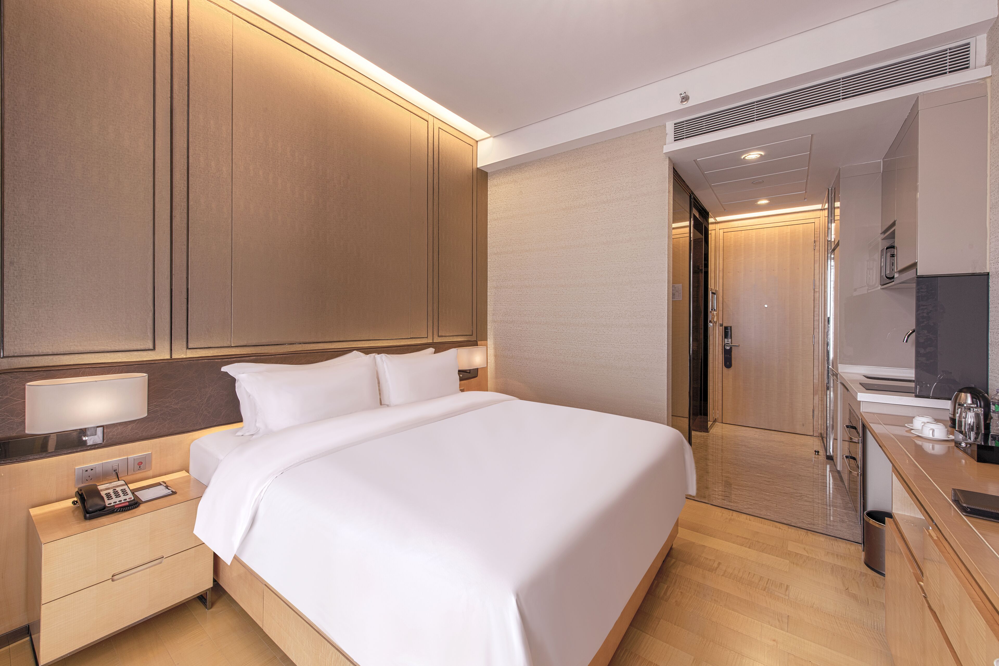 A hotel room with a large bed, bedside tables, a desk, and a mirror.