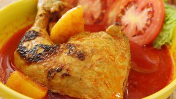 A roasted chicken with vegetables in a yellow bowl.