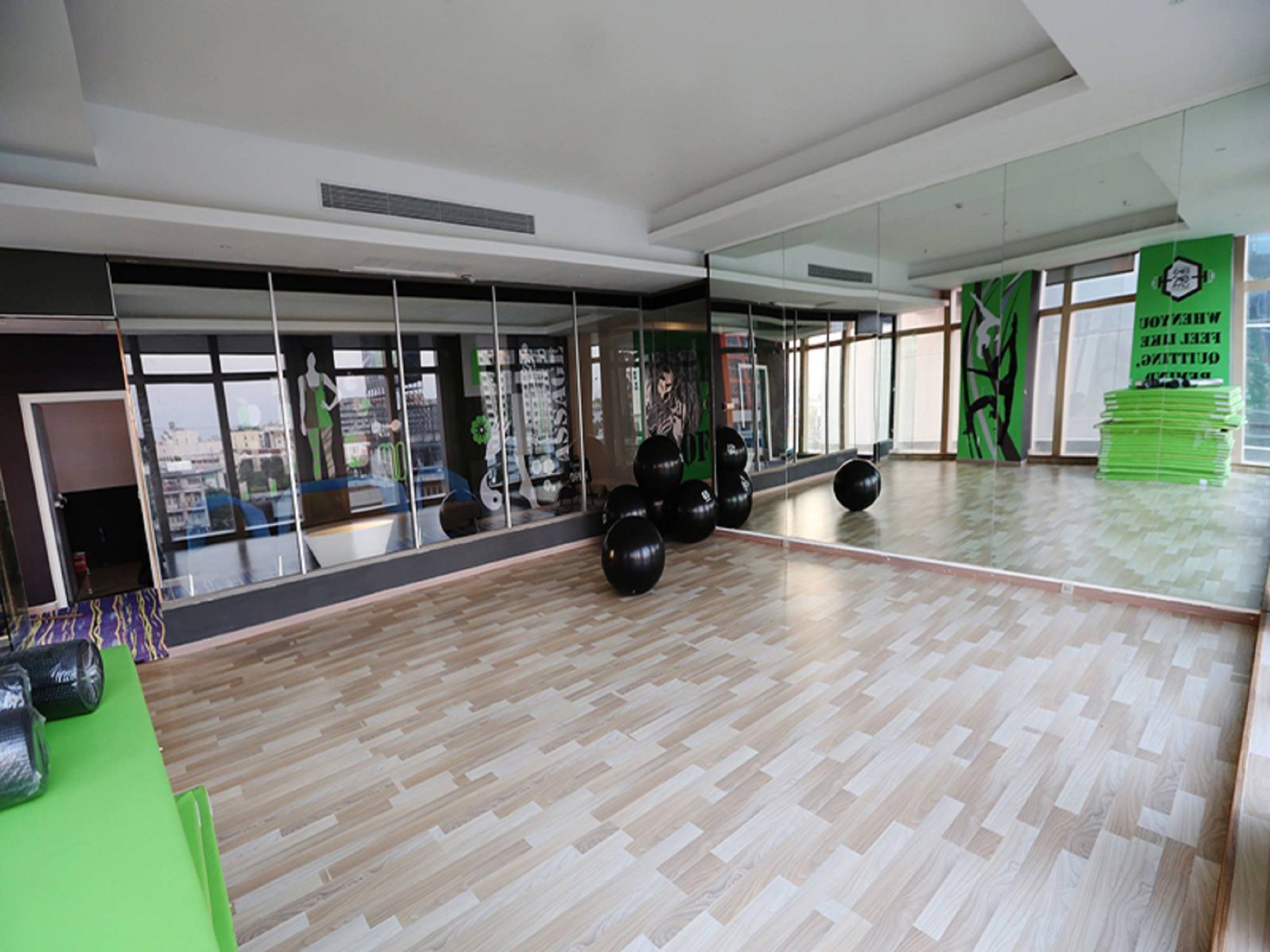 A spacious room with a large mirror, exercise balls, and a green table with dumbbells.