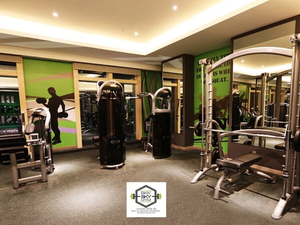 A gym with various exercise machines, a mirror, and motivational posters on the walls.