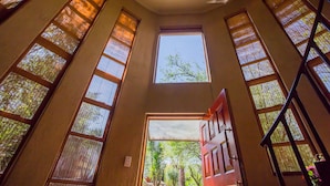 A high-ceilinged room with large windows and a view of greenery outside. - Moonflower Cottages (Randburg)