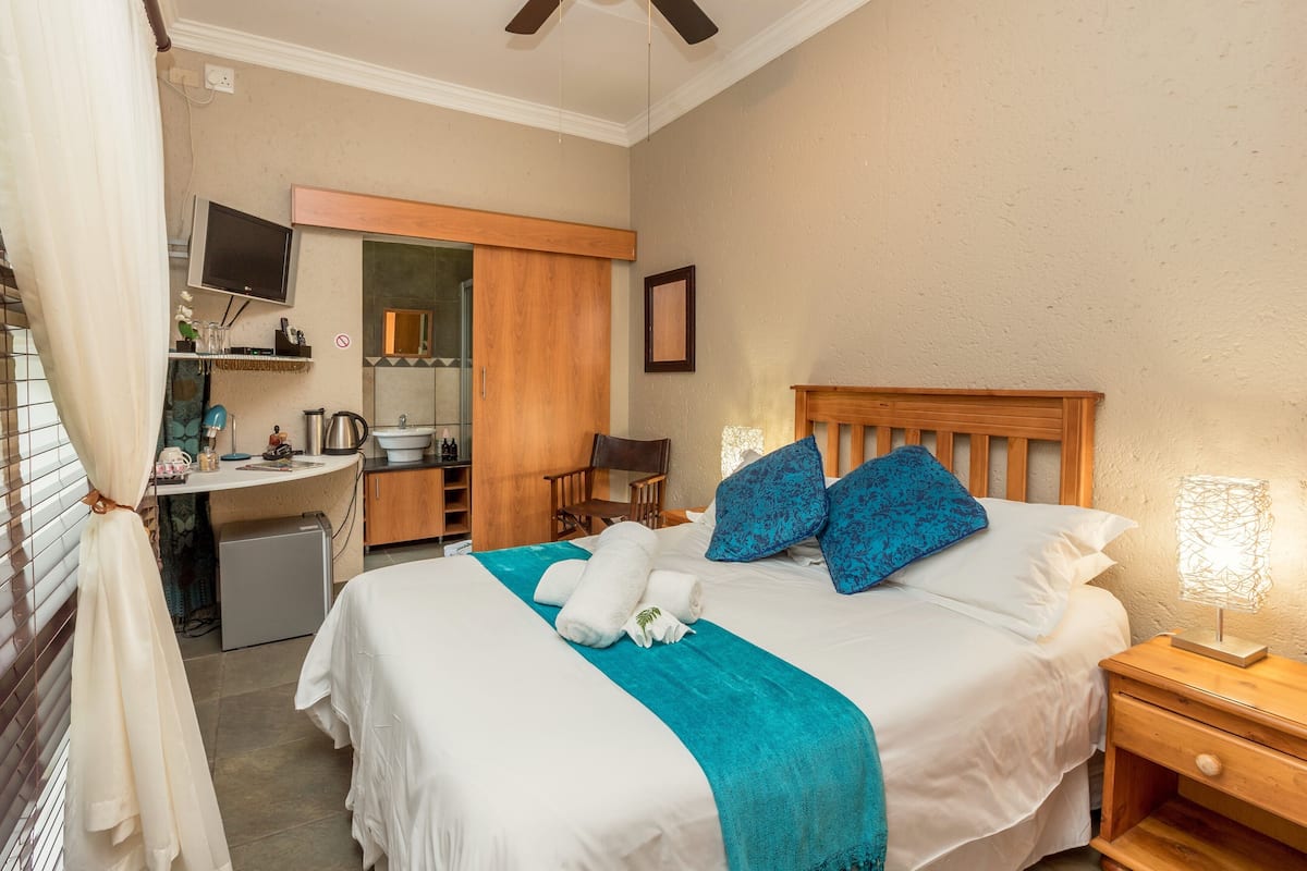 A hotel room with a bed, bedside table, and a desk with a chair.