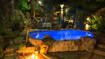 Relax by the serene pool surrounded by lush greenery and a fire feature.