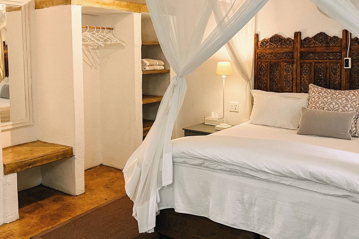 Une chambre à coucher avec un lit à baldaquin, une table de chevet, une lampe et une tête de lit en bois.