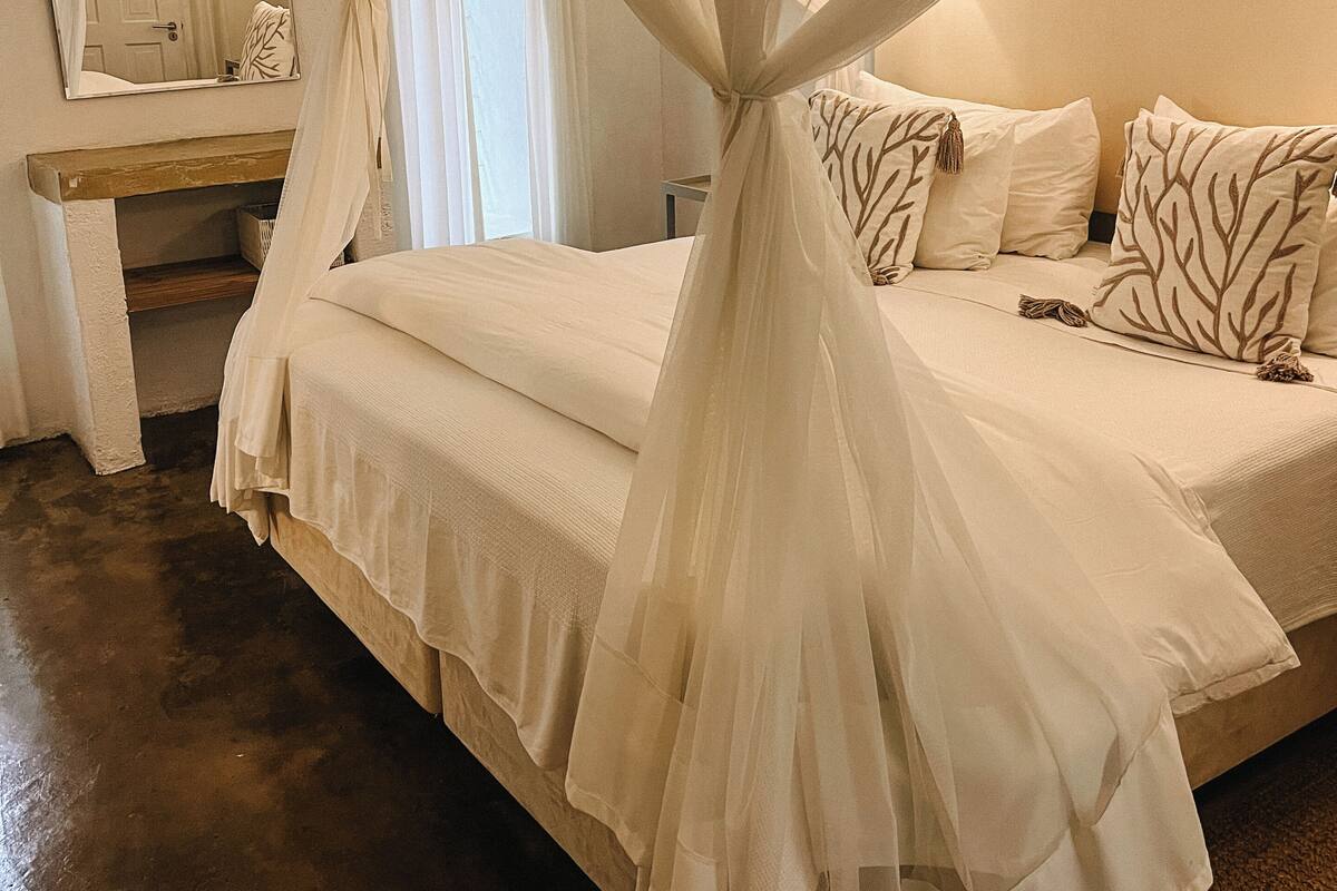 Une chambre à coucher avec un lit, une table de chevet, un miroir et un couvre-lit à baldaquin.
