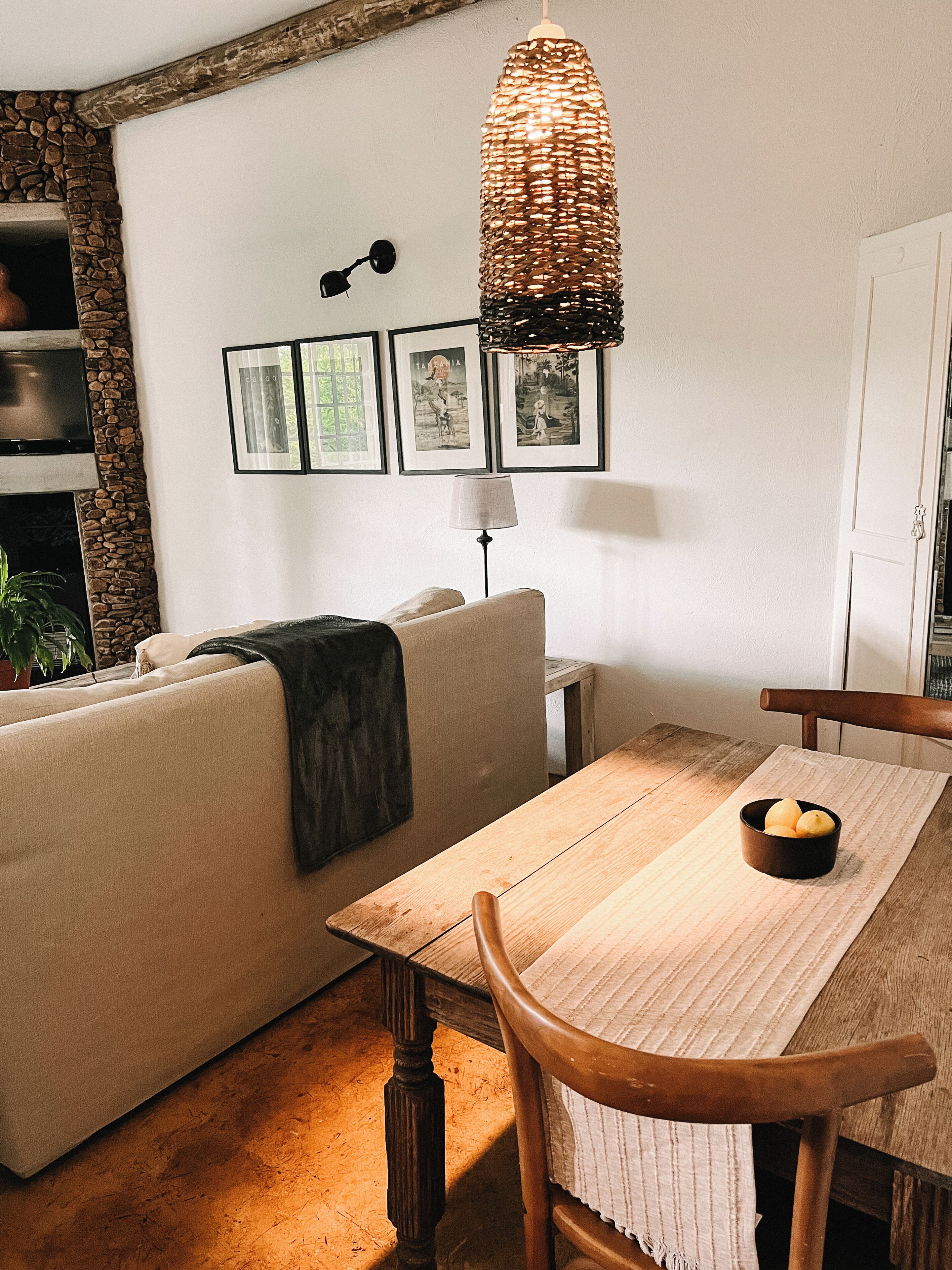 Ein Wohnzimmer mit Sofa, Esstisch, Lampe und gerahmten Bildern an der Wand.