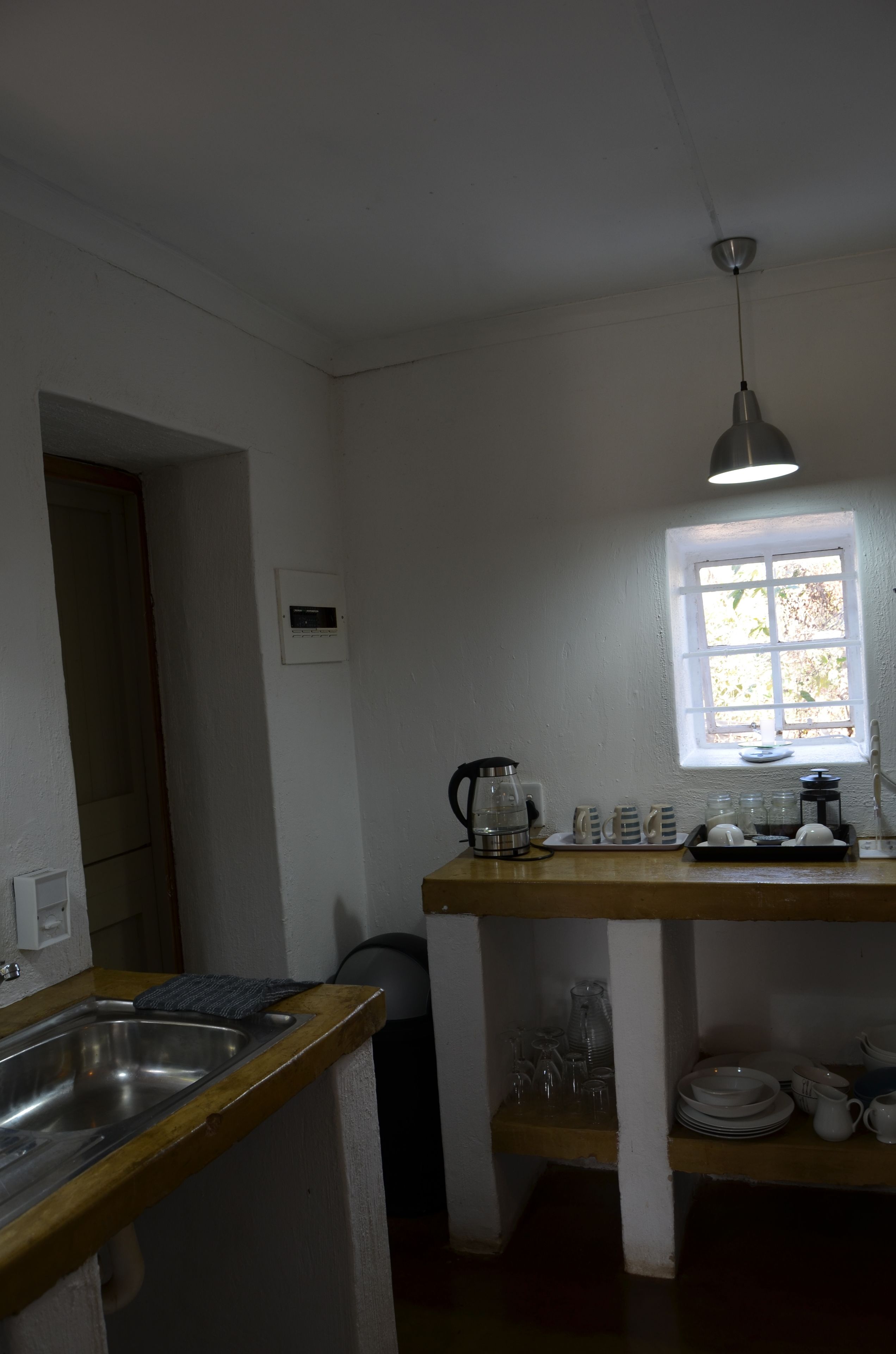 Una pequeña cocina con encimera de madera, un lavamanos, una ventana y una lámpara en el techo.