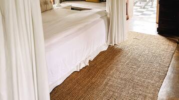 A bedroom with a canopy bed, a wooden floor, and a view of the outside.