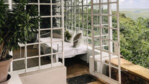 A room with a bed, a potted plant, and a view of the outdoors. - Ashbourne Country Escape (Mbombela)