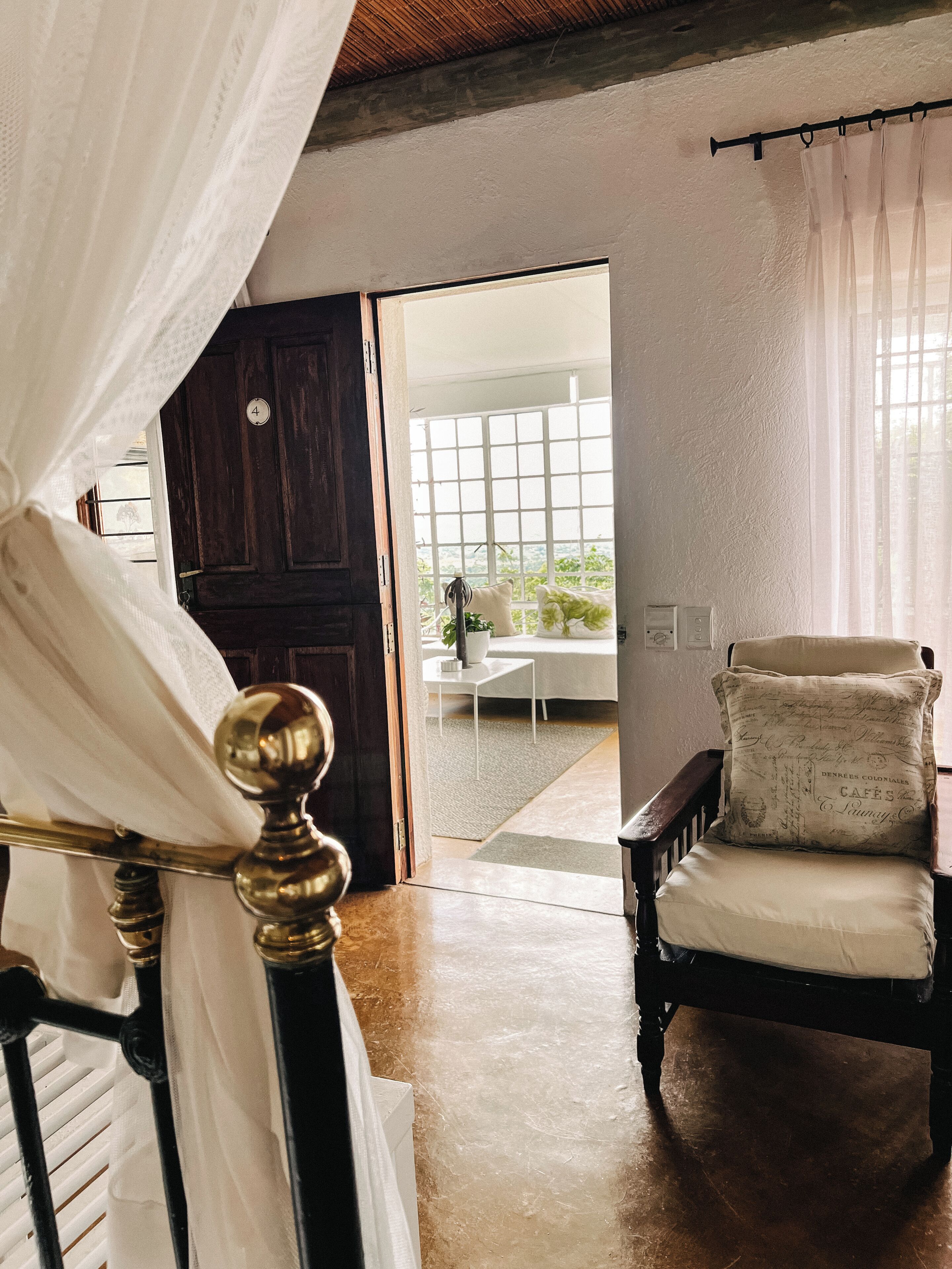 A room with a bed, a chair, a window, and a door.