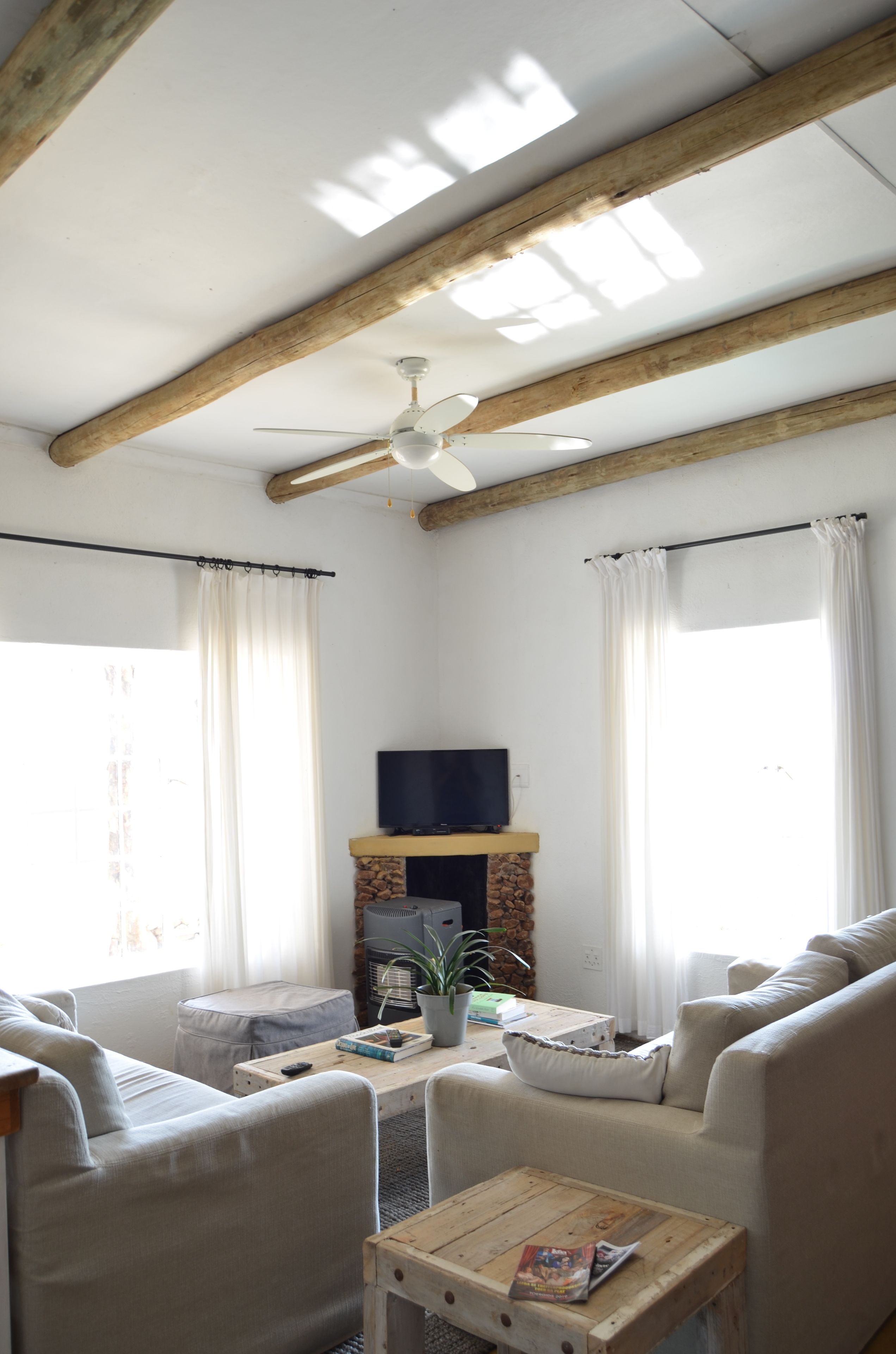 A cozy living room with a fireplace, a television, and a ceiling fan.