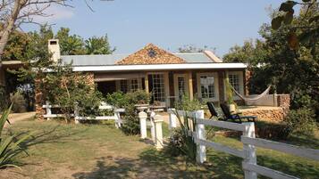 A house with a stone roof, a white fence, and a hammock.