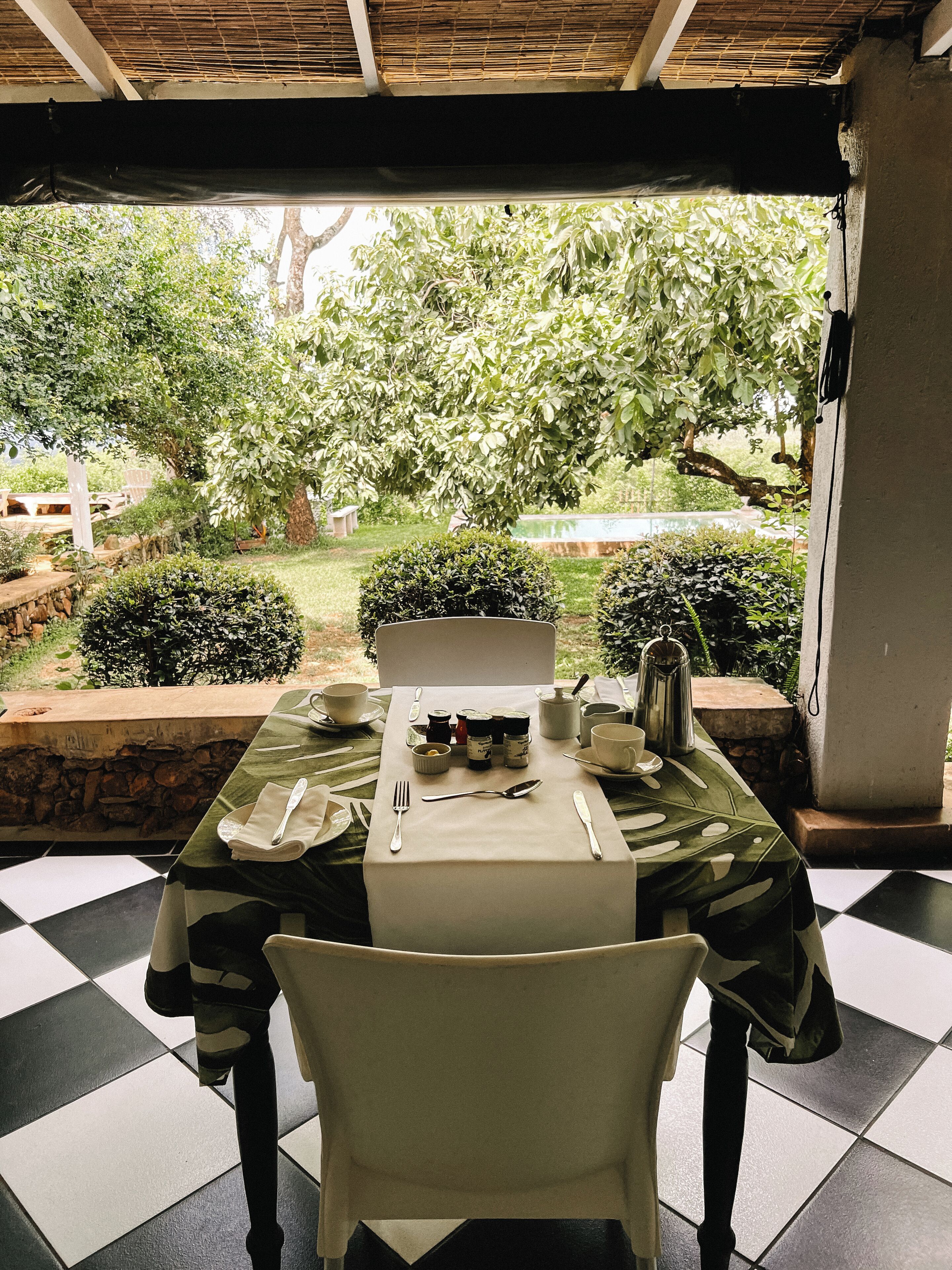 A dining table set outdoors with a view of a garden.