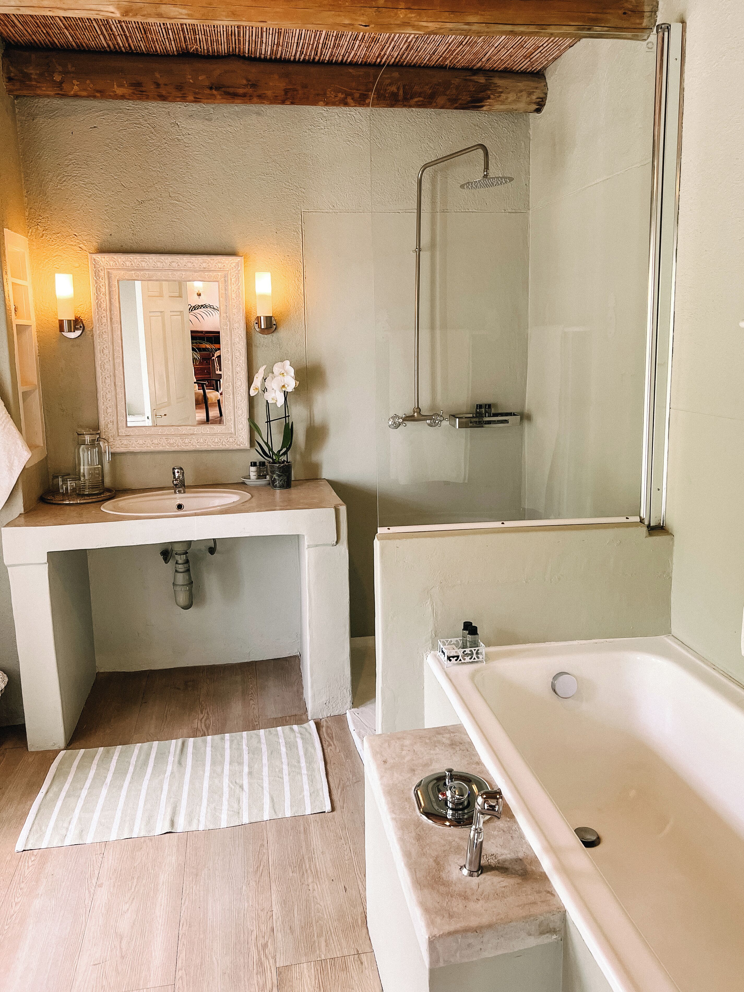 A bathroom with a bathtub, a shower, a sink, and a mirror.