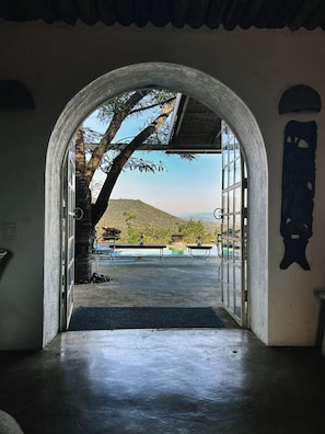 An arched doorway leading to an outdoor area with a view of a hill and a pool. - Ashbourne Country Escape (Mbombela)