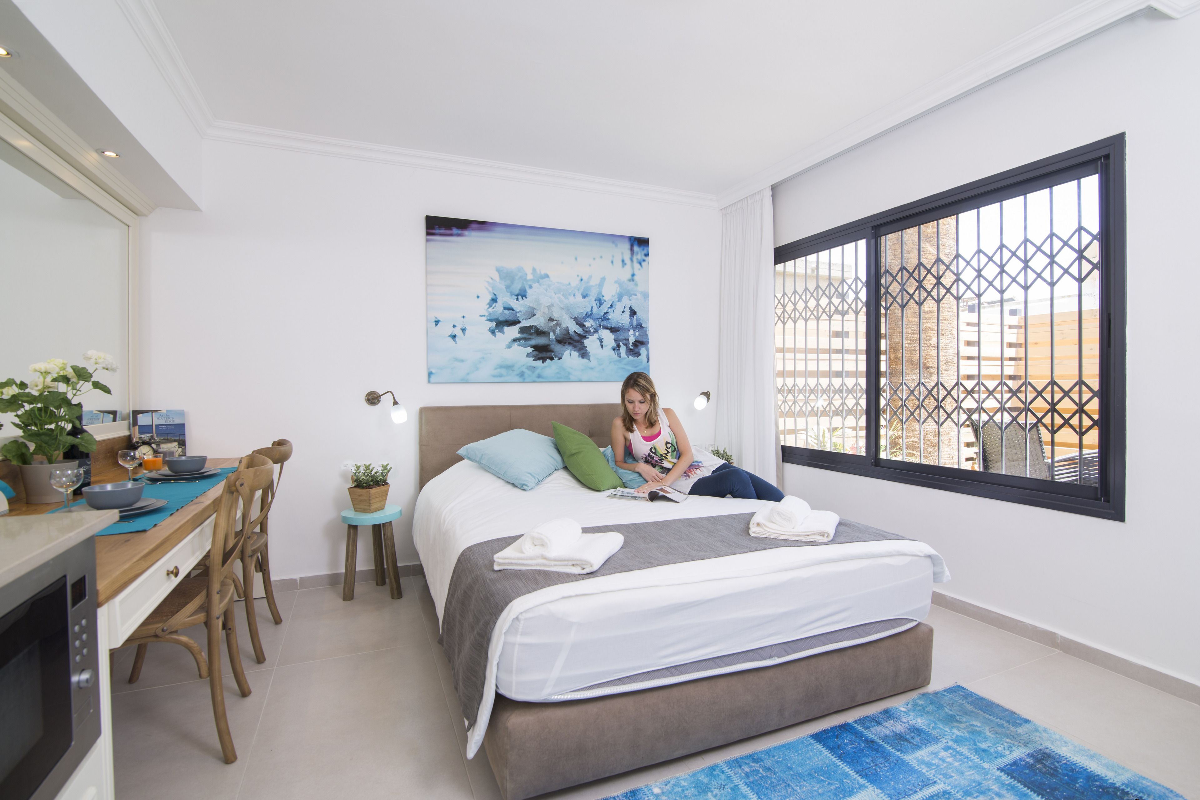 Une chambre d’hôtel moderne équipée d’un lit, d’un bureau et d’une fenêtre donnant sur des immeubles.