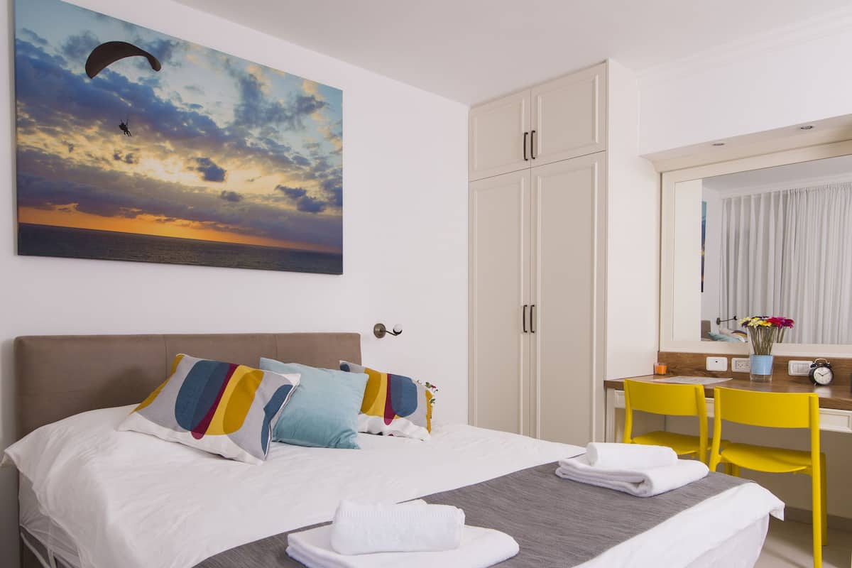 A bedroom with a bed, a desk, and a chair.