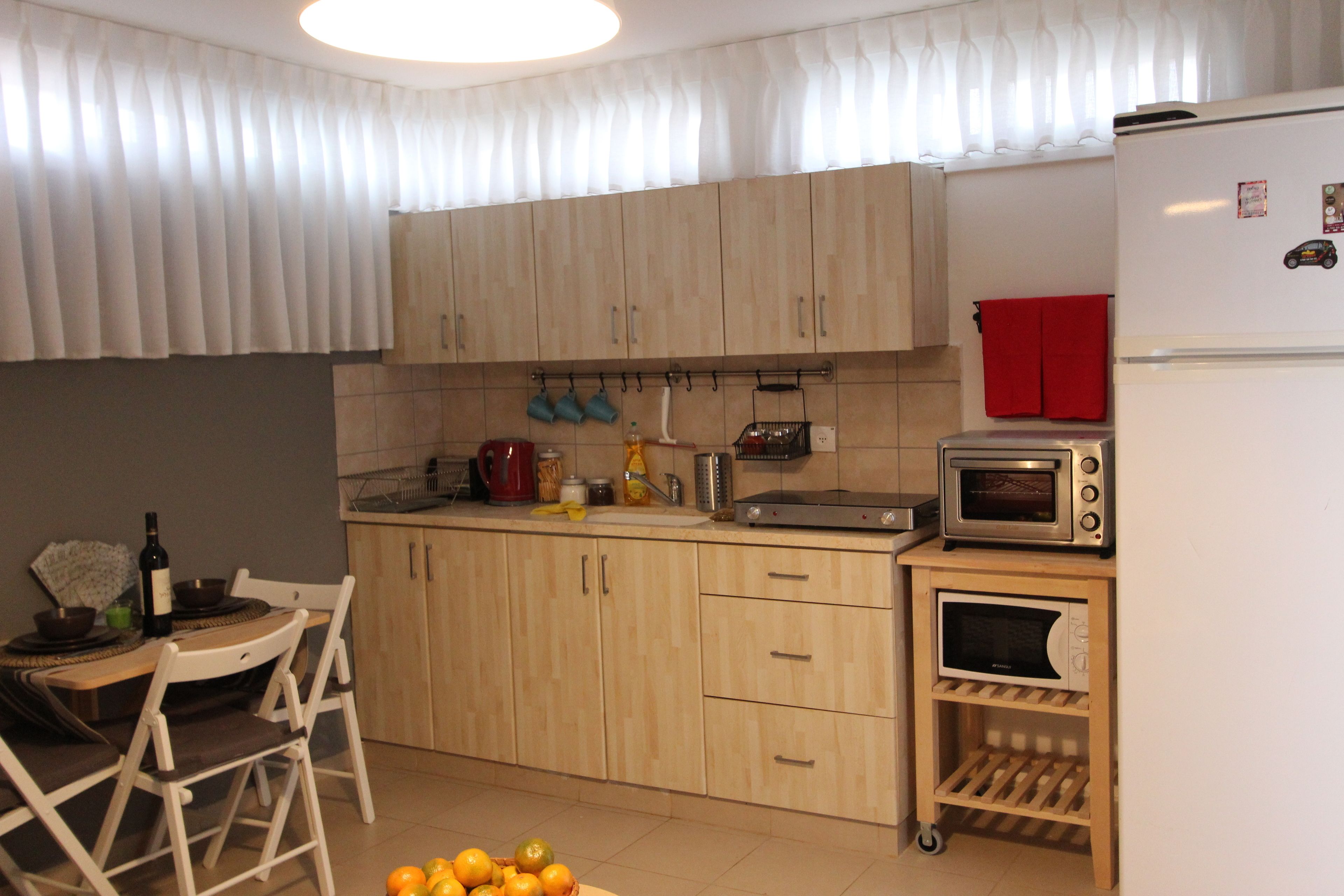 A kitchen with wooden cabinets, a microwave, a toaster, and a small refrigerator.