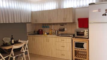A kitchen with wooden cabinets, a microwave, a toaster, and a small refrigerator.
