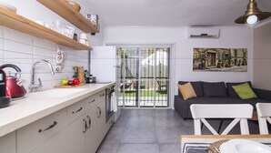 A modern kitchen with a white countertop, stainless steel appliances, and a sliding glass door leading to a patio. - HaBaitBe Matityahu (Beersheba)